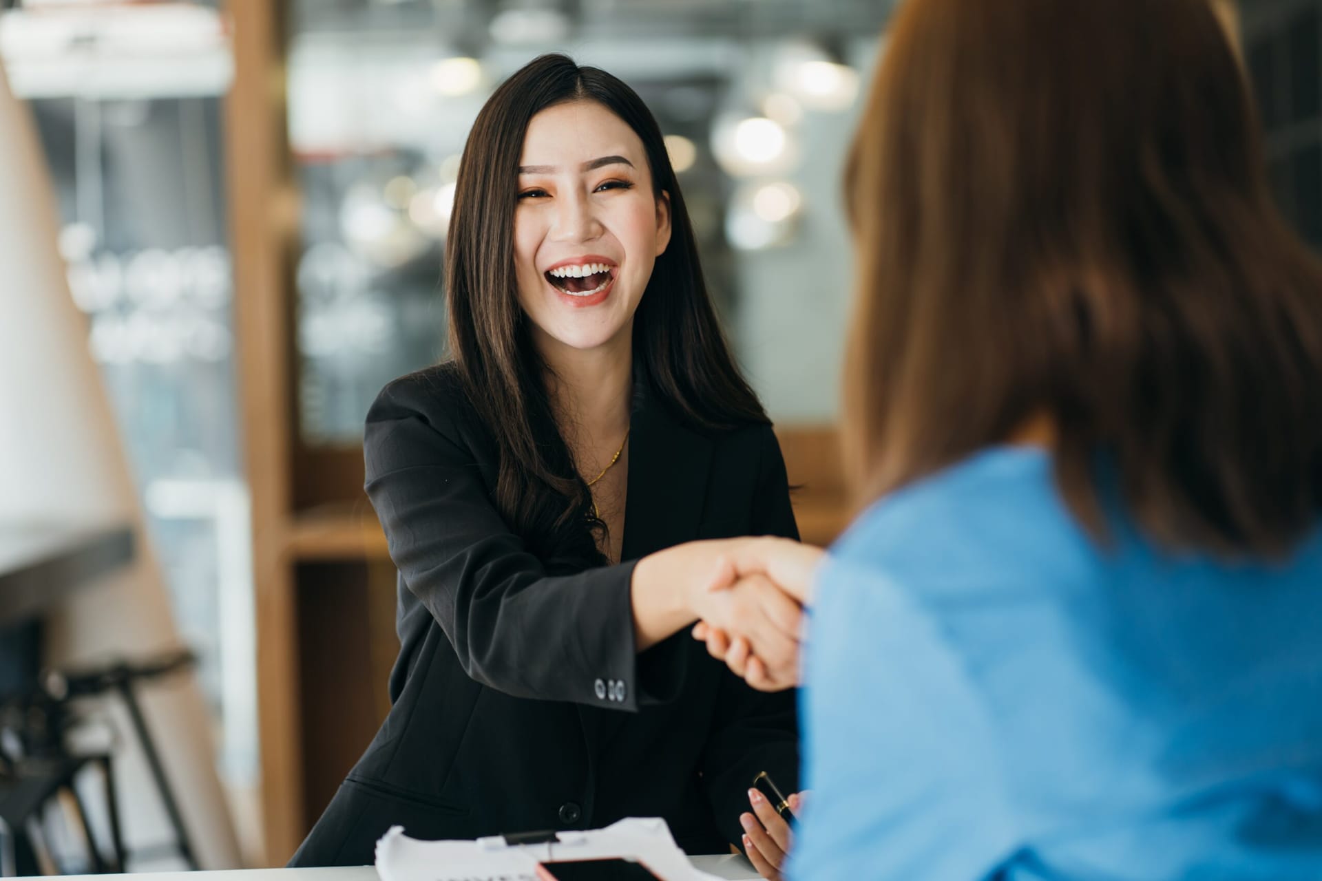 Young Asian careerwoman shaking hands with someone